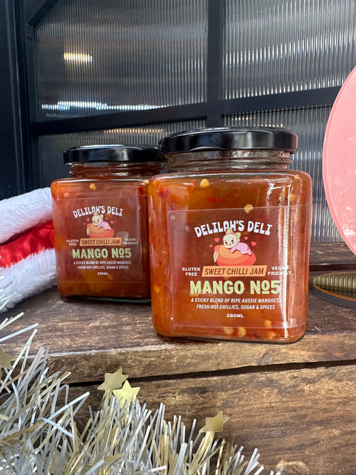 Jar of Delilah's Deli Mango No.5 on a wooden surface with decorative elements