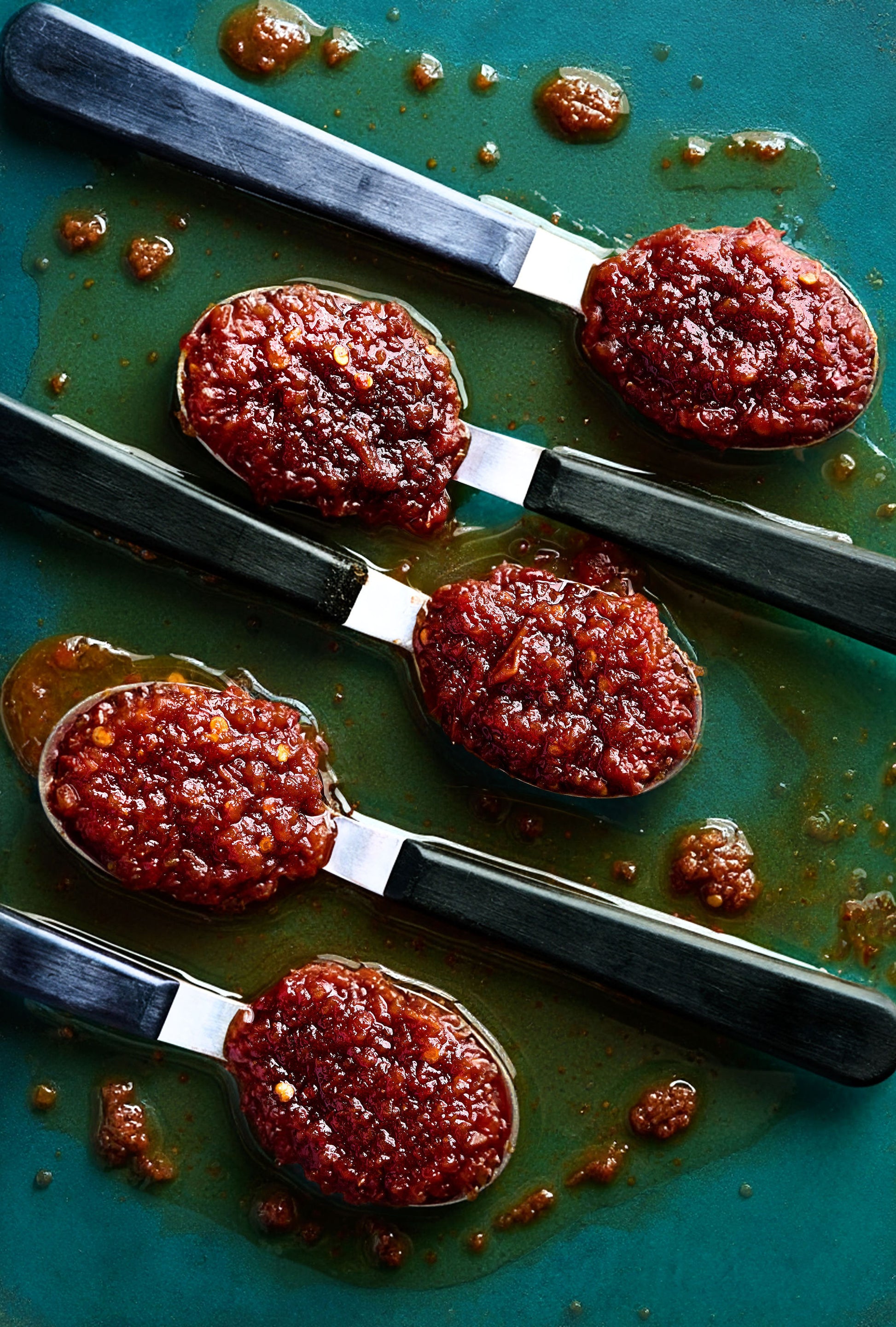 Red paste on spoons on a green surface