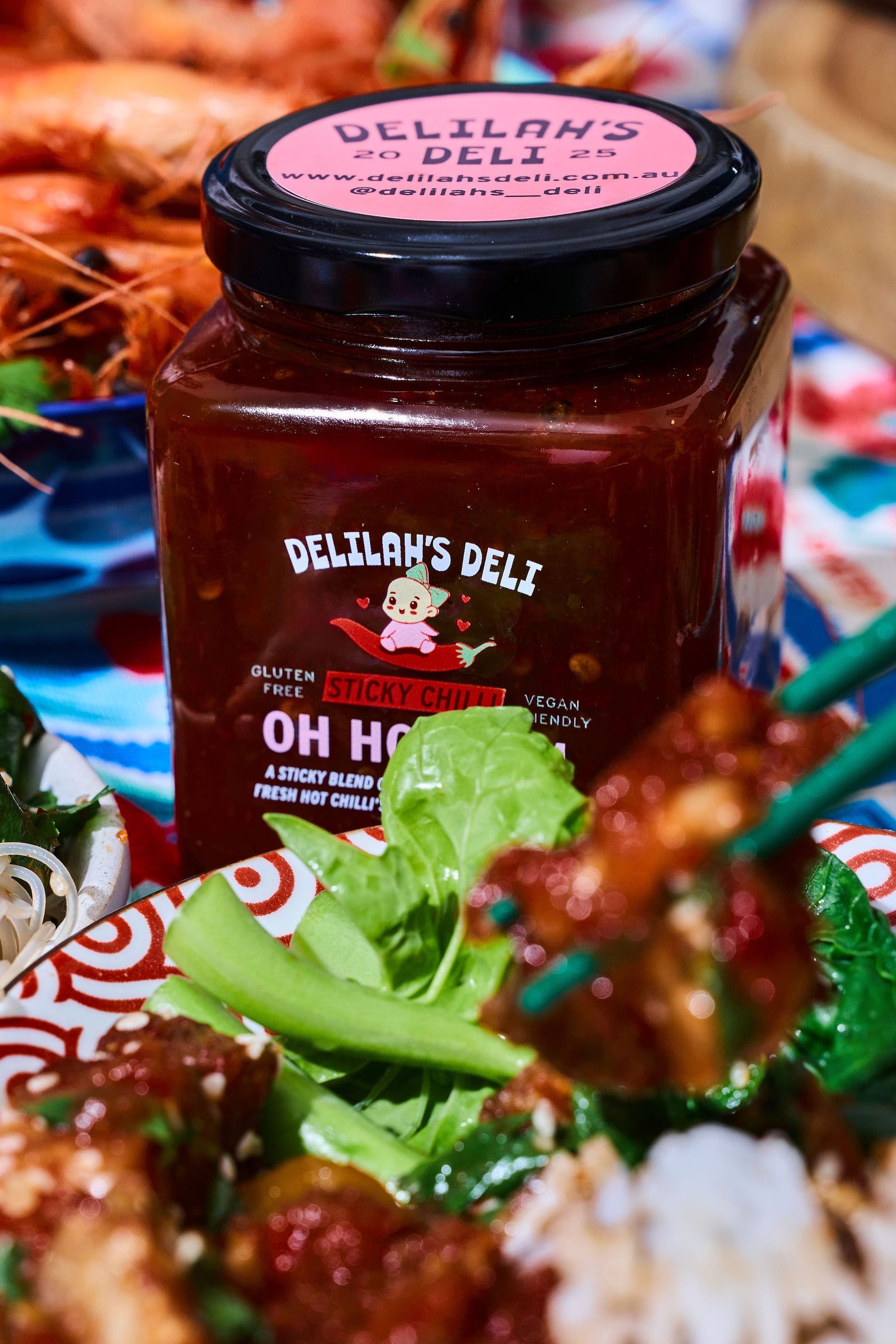 Jar of Delilan's Deli spicy chilli on a plate with salad and prawns