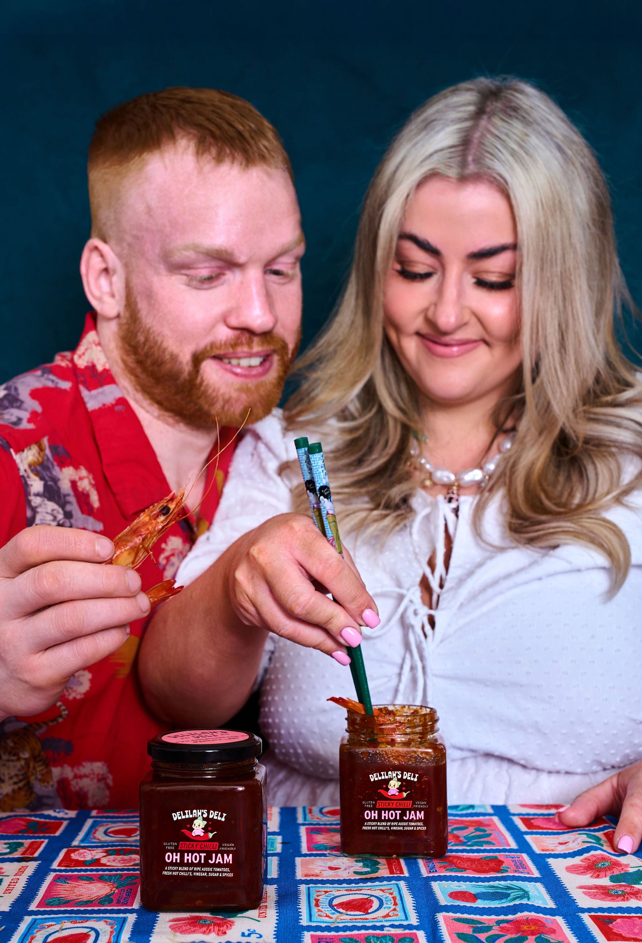 Two people tasting 'Oh Hot Jam' at a table with a colorful tablecloth.